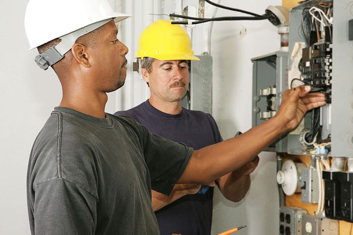 Two electricians working on electric panel