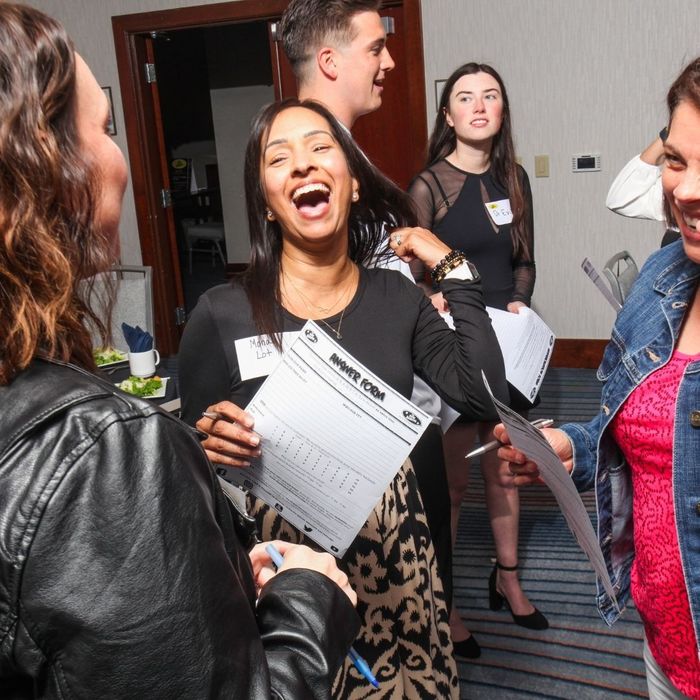 A woman in the center laughs enthusiastically while holding a mystery Answer Form and talking with two other guests during an interactive true crime show. A woman in the center laughs enthusiastically while holding a mystery Answer Form and talking with two other guests during an interactive true crime show.