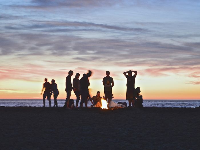  A group of people around a campfire at the beach.