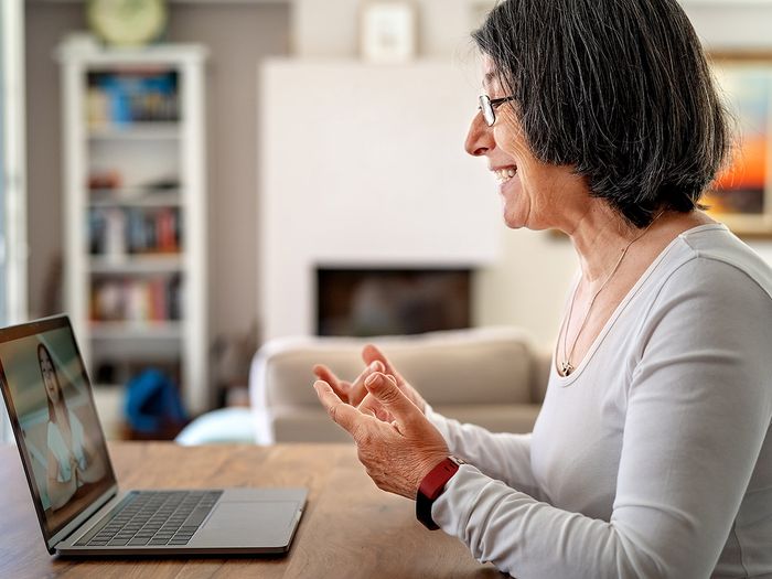 Older female teacher has virtual class with a student on her laptop at home.