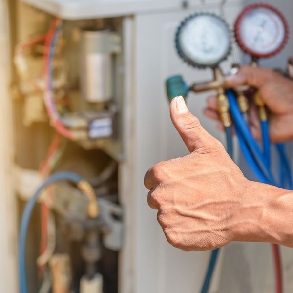 Closeup of a hand giving a thumbs up in front of HVAC equipment