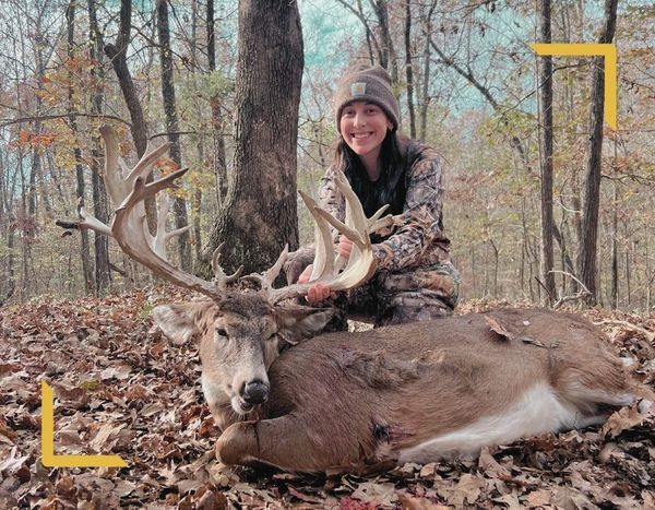 young woman holding antlers of dead deer in leaves