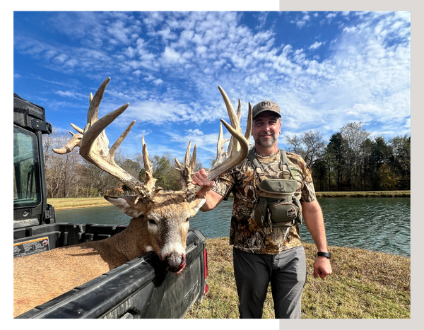 A man standing with his trophy whitetail deer in the back of a 4 wheeler