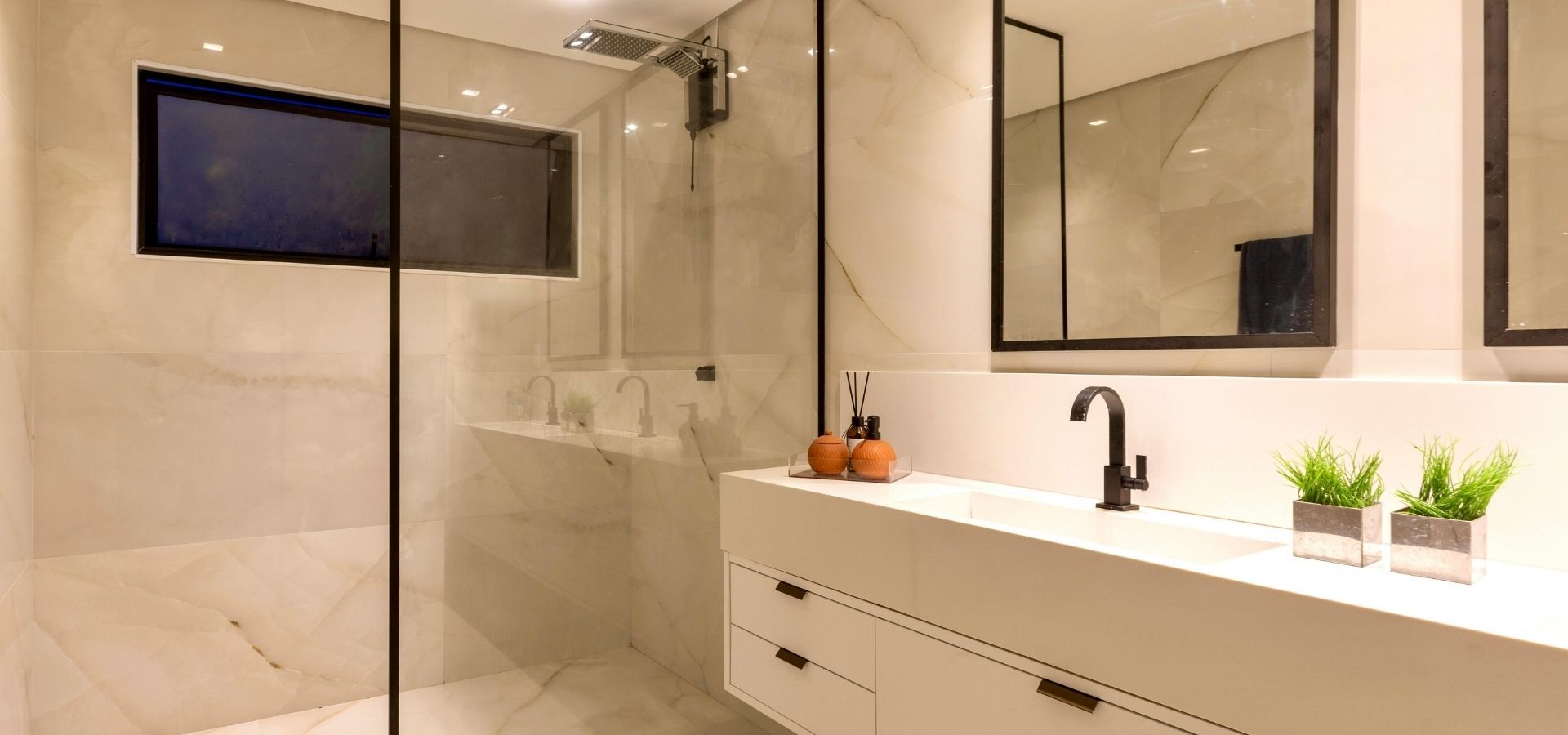 Sleek master bathroom with a floating white vanity, matte black hardware, and a large walk-in glass shower with marble-effect wall tiles.