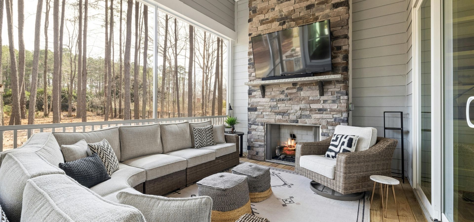 Luxury screened-in patio featuring a floor-to-ceiling stacked stone fireplace, custom mantel, and comfortable outdoor sectional seating.