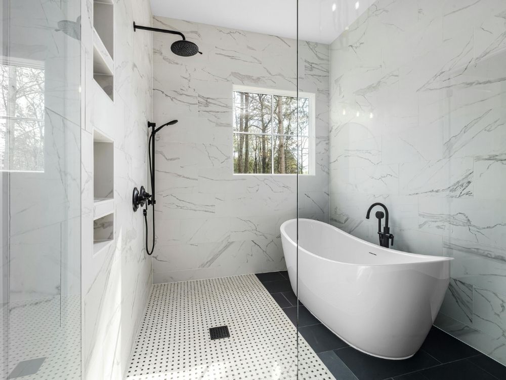 Luxury spa bathroom featuring a freestanding soaking tub, floor-to-ceiling marble wall tile, and a walk-in shower with matte black fixtures.