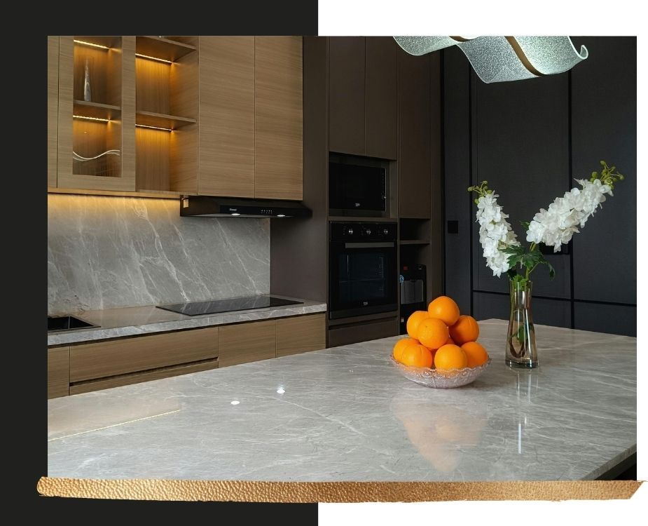 Modern kitchen detail featuring grey marble countertops and backsplash, integrated appliances, and warm LED under-cabinet task lighting.