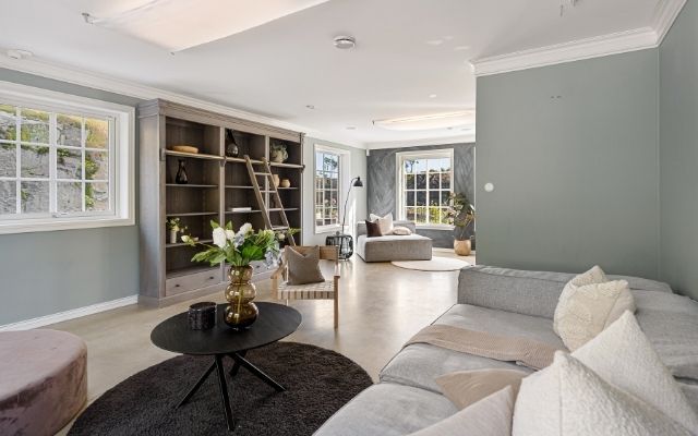 Spacious living area showcasing a smooth, professional sage green interior paint job with crisp white crown molding.