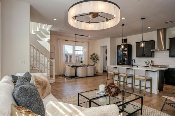 Open-concept main floor showing a seamless transition between a modern kitchen with dark cabinetry and a bright, airy living room with warm hardwood floors.