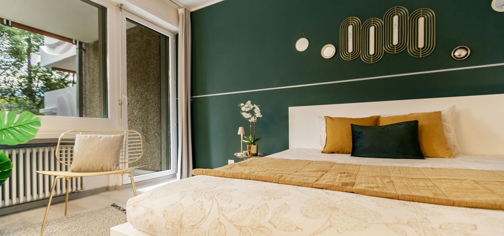 Modern bedroom featuring a professional deep emerald green accent wall with a thin white architectural pinstripe and minimalist gold wall decor.