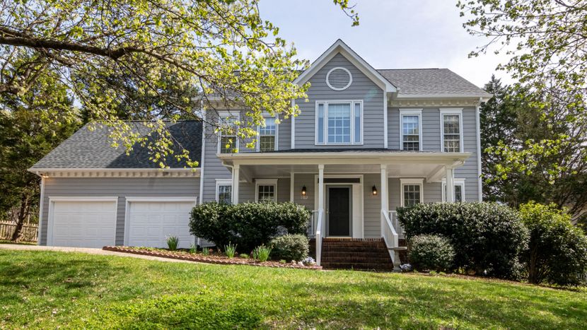 The front yard of a big grey two story house
