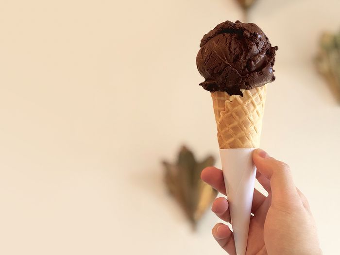 Person holding chocolate gelato on a waffle cone