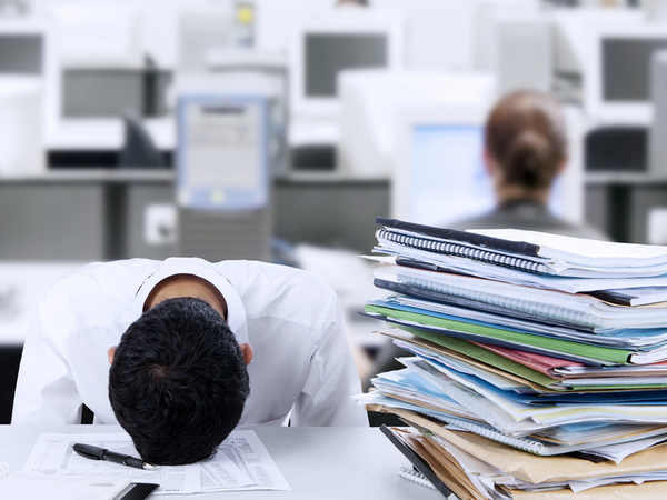 overwhelmed employee rests head on desk