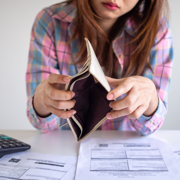 A women holding open an empty wallet with bills and a calculator