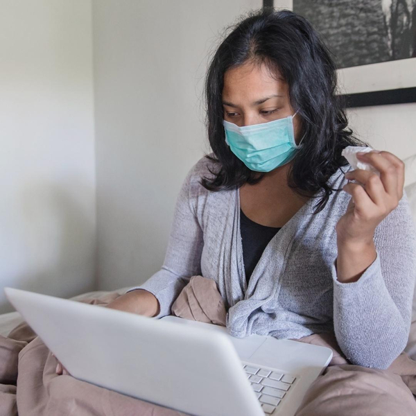 woman working from home sick wearing mask