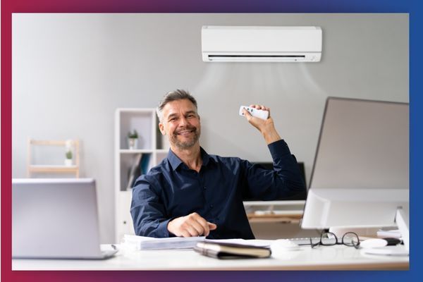 smiling man using remote to control ductless heating system