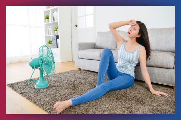 Woman sitting in front of fan in home