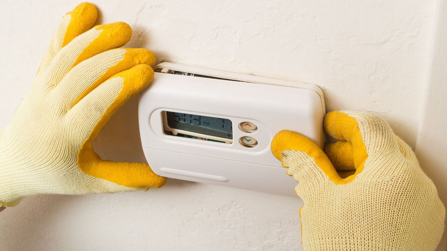 gloved hands adjusting a thermostat