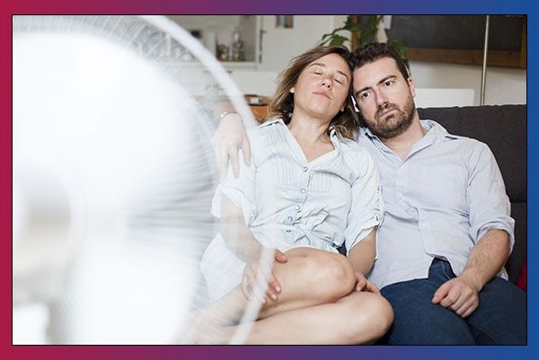 Couple sitting in front of fan in home