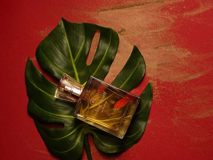 A perfume bottle laying on a monsterra leaf