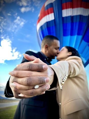 Couple kissing in front of hot air balloon