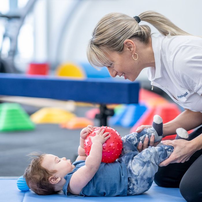 Infant with a ball working with a pediatric physical therapist.