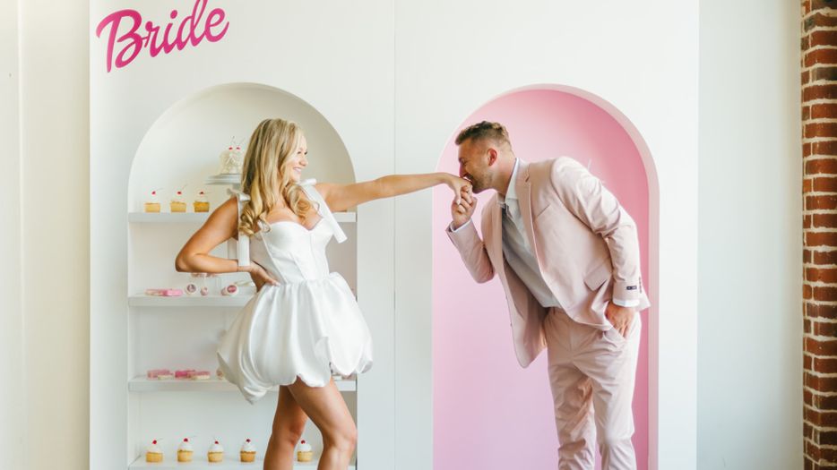couple posing in front of a Barbie themed wall