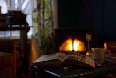 Open book open on table next to coffee cup in front of fireplace.jpg