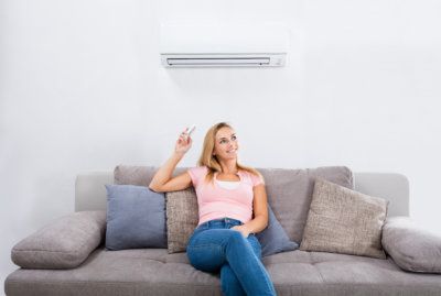 Woman Operating Air Conditioner With Remote Control.jpg