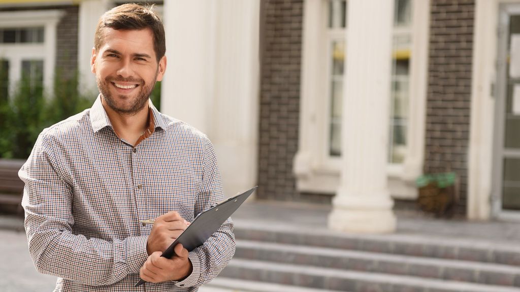 man holding clipboard in front of home