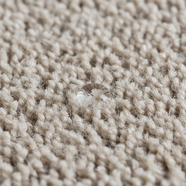 A magnified view of durable, resilient nylon carpet fibers, with a small droplet of water beading on the surface.