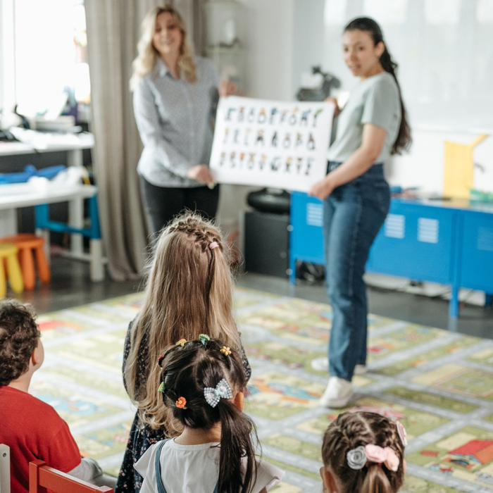 teachers presenting printed poster to children in classroom