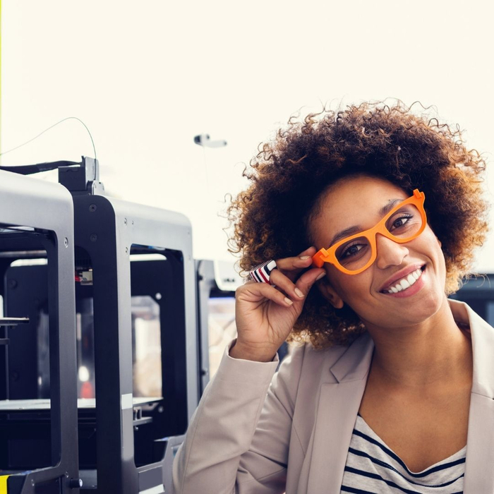 A woman smiling at the camera with printers in the background