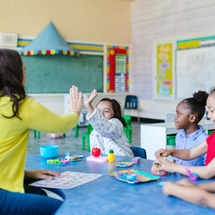 teacher giving student high five in colorful classroom