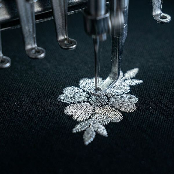 A machine quickly stitches dense thread on fabric.