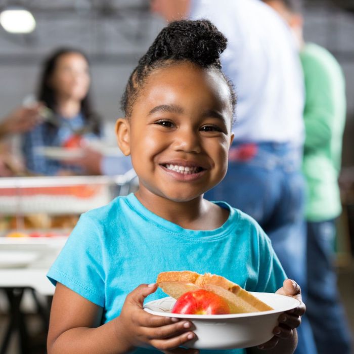 A smiling girl holding a bowl of food from a soup kitchen A smiling girl holding a bowl of food from a soup kitchen