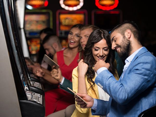 a couple excited at a slot machine as others look