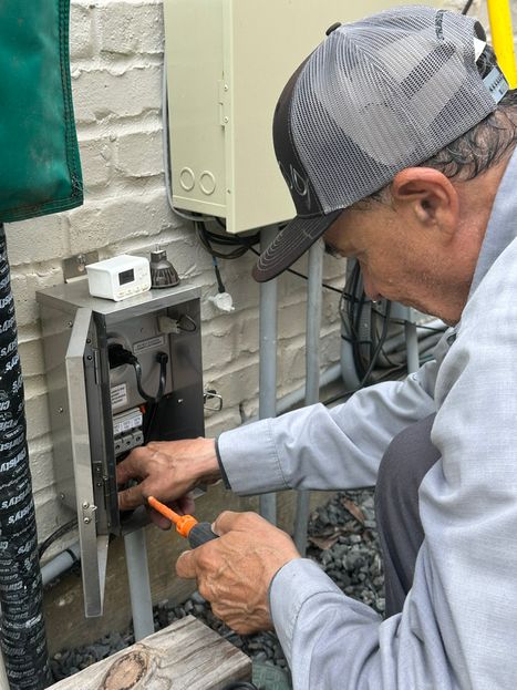Licensed electrician from Stirling Electric & Irrigation making outdoor wire connections to power landscape lighting and features in West University Place Stirling electrician wiring outdoor landscape power in West University Place