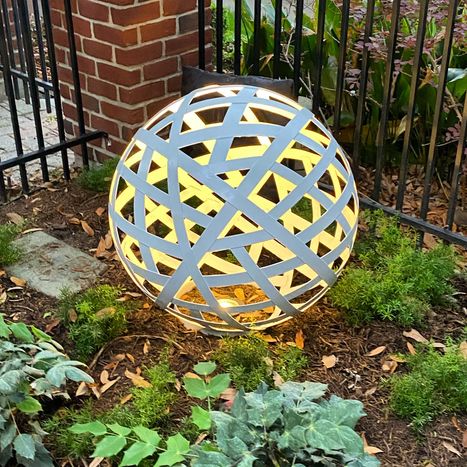 Stirling Electric & Irrigation installed landscape lighting to highlight a globe-like art piece in a West U homeowner’s yard, blending form and function Illuminated sculptural globe art piece in West University Place yard