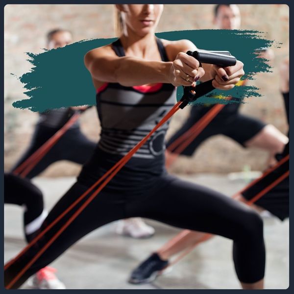 Woman doing a low lunge exercise with resistance bands in a group class.