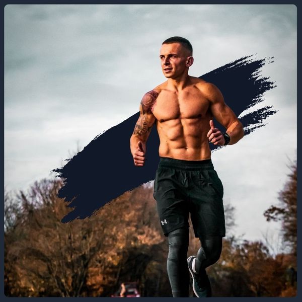 Muscular man with tattoos, shirtless and running outdoors.