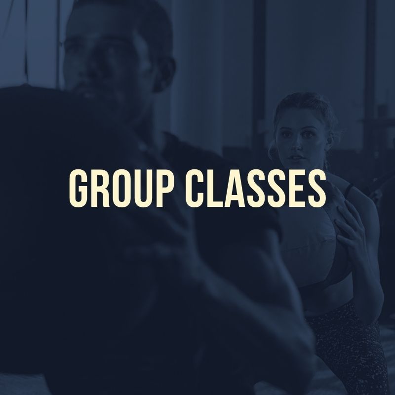 Overlay with text "GROUP CLASSES" on a dark image of people working out with medicine balls. Overlay with text "GROUP CLASSES" on a dark image of people working out with medicine balls.