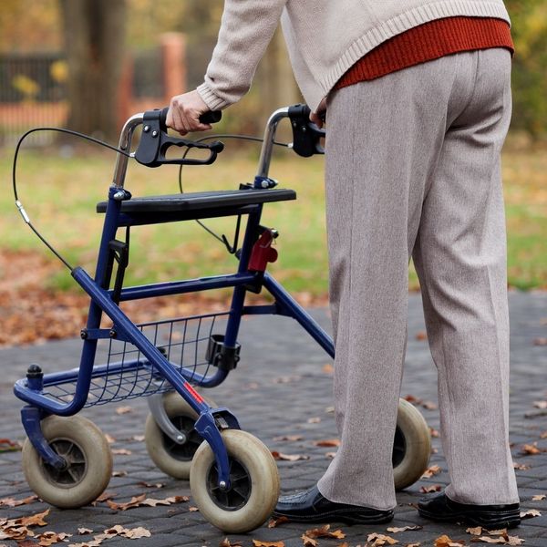 An elderly perosn using a walker.
