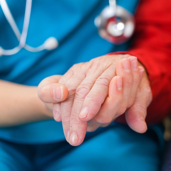 A nurse holding a patient's hand.