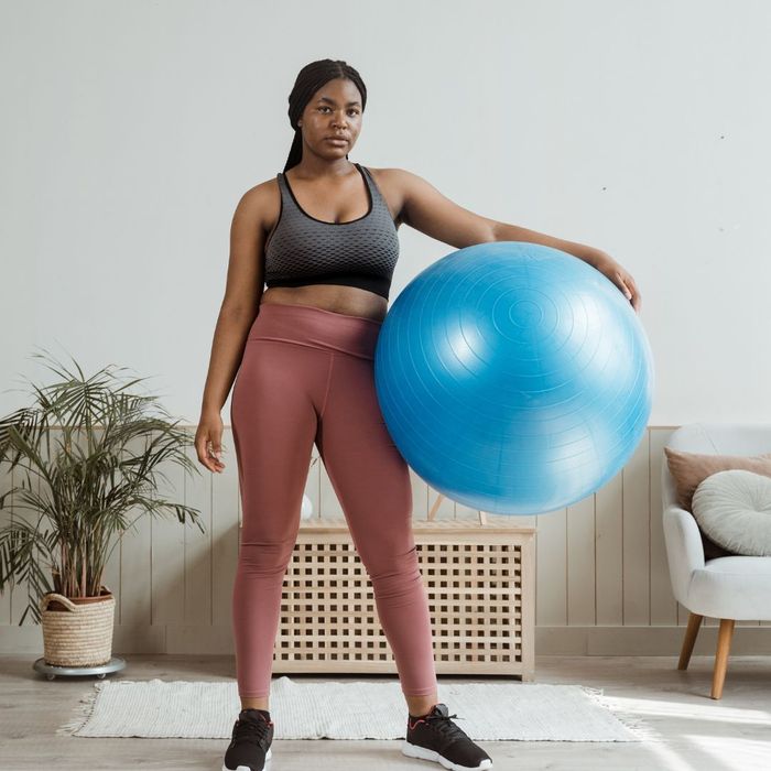 Person in exercise attire holding a stability ball