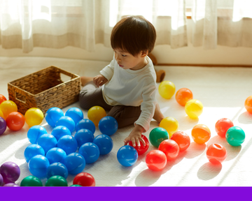 toddler playing with colorful balls. toddler playing with colorful balls.