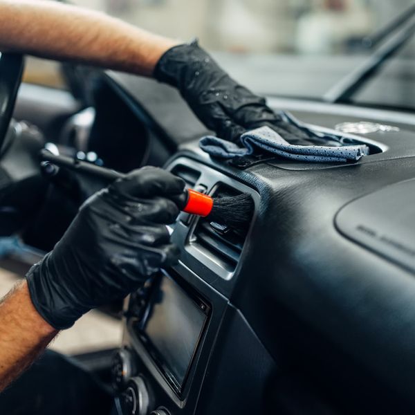 Person brushing air conditioner vents in a car. 