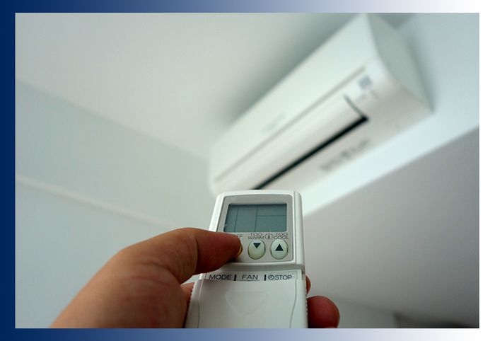 a person using a remote to turn on a ductless ac unit
