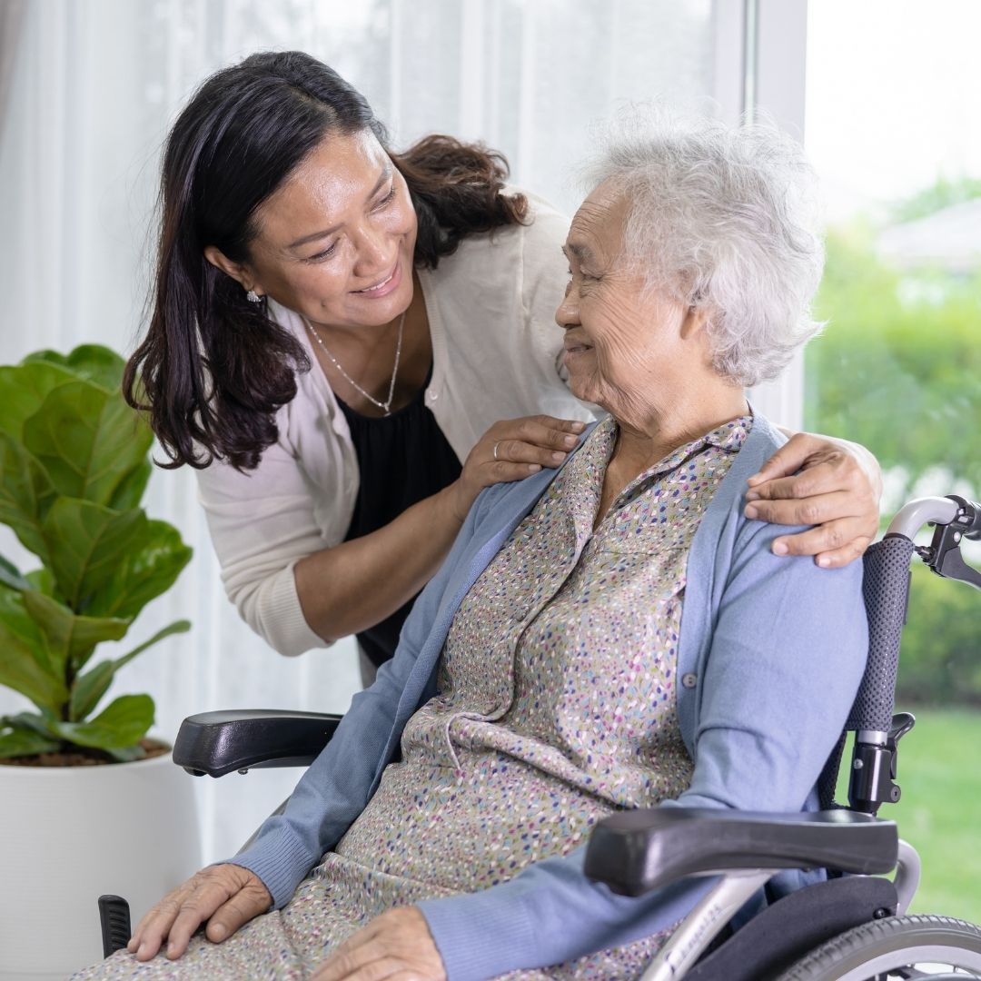 happy woman in wheelchair with caretaker or family mebmer