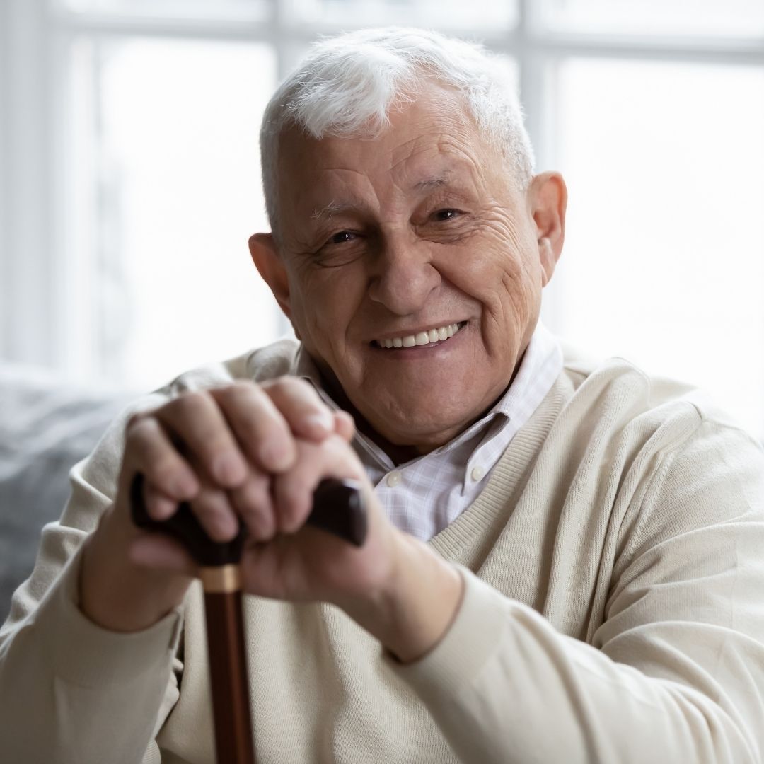 happy man on couch, smiling, with cane